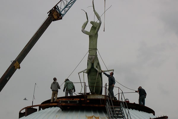 Large Praying Mantis statue being craned up onto the City Museum roof